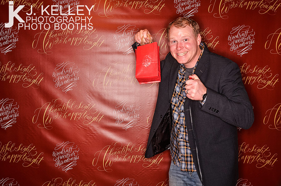 Guest with holiday party gift in photo booth at corporate event in Columbia, MO
