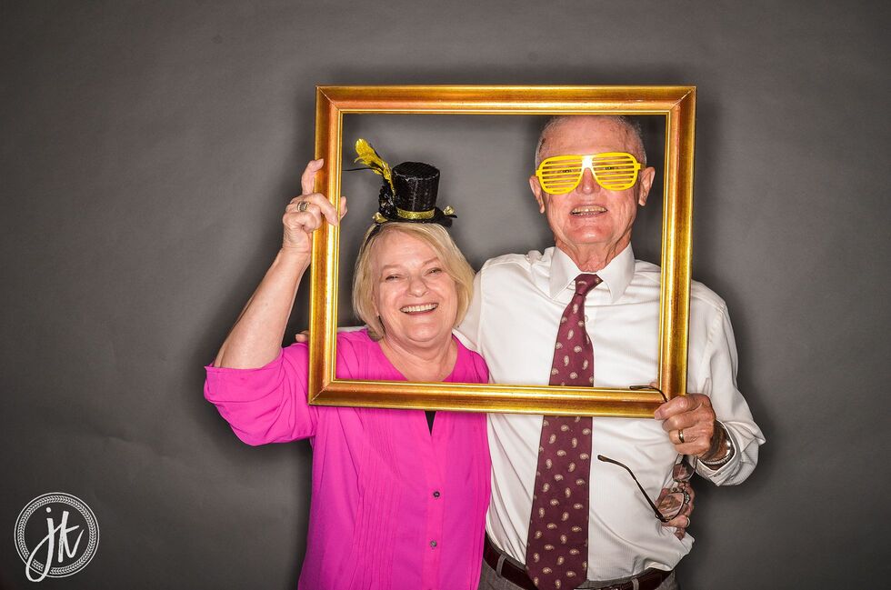 Adorable older couple using photo booth with fun picture frame prop